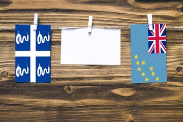 Hanging flags of Martinique and Tuvalu attached to rope with clothes pins with copy space on white...