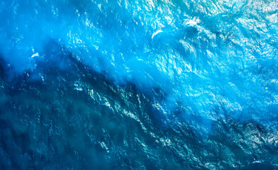 texture of the sea surface with ripples and different shades of turquoise. waves of the turquoise sea with blue layers from the sandy shores, texture view from above with drone