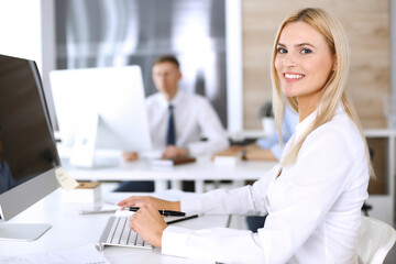 Obraz premium Business woman using computer at workplace in modern office. Secretary or female lawyer smiling and looks happy. Working for pleasure and success