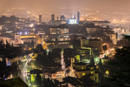 View of the rooftops, churches and towers of the Upper Town (Citt&agrave; Alta) of Bergamo city at night. Bergamo, Lombardy, Italy.