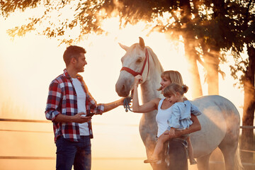  Smiling family have a fun with a beautiful horse on the countryside .