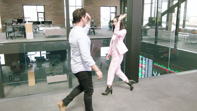 Business colleagues giving high 5 as they pass in office, filmed in bullet time action effect