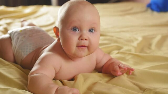 A chubby four-month-old baby lies on his tummy on the couch. Close up shot.