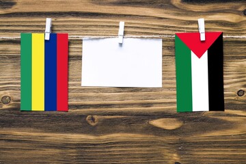Hanging flags of Mauritius and Palestine attached to rope with clothes pins with copy space on...