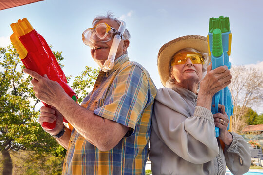 Modern Senior couple have fun playing with  water gun.
