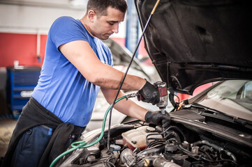 Auto mechanic repairer changing spark plugs on the car