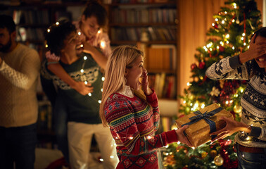 Woman surprising her friend girl with a romantic present at Christmas.