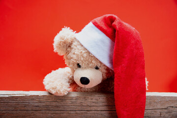 Obraz premium Teddy bear with santa hat, red color background