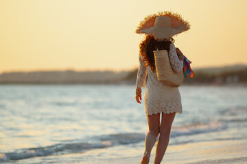 elegant middle age woman on beach at sunset walking