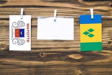 Hanging flags of Mayotte and Saint Vincent And The Grenadines attached to rope with clothes pins...