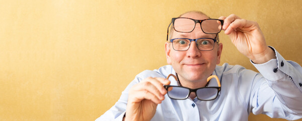 A man tries on reading glasses. He tests glasses and has three points on his face. Portrait of a...