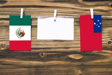 Hanging flags of Mexico and Samoa attached to rope with clothes pins with copy space on white note...