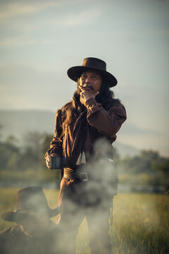 The cowboy standing in a cup of coffee While talking on the camping in the sunset
