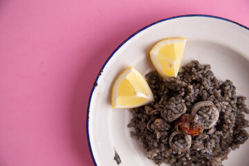 Plate of black rice with squid and prawns or Valencian black paella