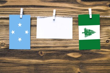 Hanging flags of Micronesia and Norfolk Island attached to rope with clothes pins with copy space...