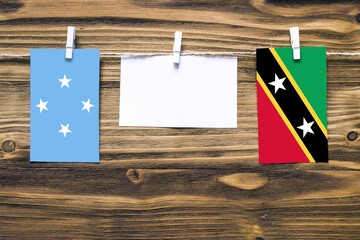 Hanging flags of Micronesia and Saint Kitts And Nevis attached to rope with clothes pins with copy...