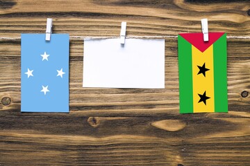 Hanging flags of Micronesia and Sao Tome And Principe attached to rope with clothes pins with copy...