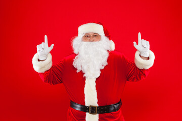 Fototapeta na wymiar Santa Claus pointing in blank a place, red background.