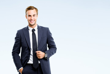 Happy smiling confident businessman in black suit, isolated over grey background. Business success...