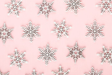 Christmas background. White snow decorations on a pink background.