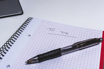 libreta y bolígrafo sobre mesa blanca con ordenador portátil