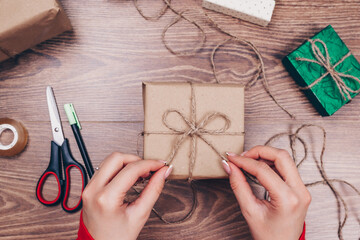 Fototapeta na wymiar Gift wrapping. Woman packs holiday gifts at home on wooden table.