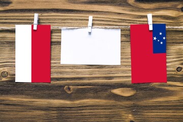 Hanging flags of Monaco and Samoa attached to rope with clothes pins with copy space on white note...