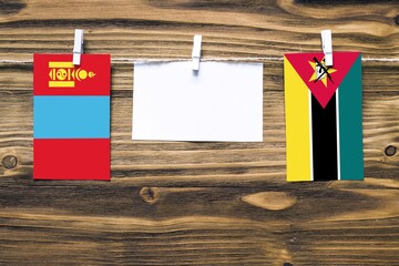 Hanging flags of Mongolia and Mozambique attached to rope with clothes pins with copy space on...