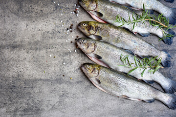 Rainbow trouts on a stone board with herbs