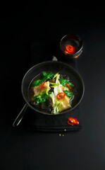 Traditional vietnamese soup with vegetables and mushrooms on black background