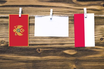 Hanging flags of Montenegro and Poland attached to rope with clothes pins with copy space on white note paper on wooden background.Diplomatic relations between countries.