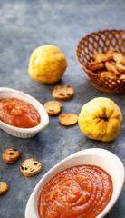 Homemade jelly quince in a white crockery containers with some quince fruits and little toasts to spread.