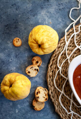 Top view to some quinces and jelly quince in a white crockery containers and little toasts to spread.