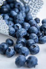 Spilled blueberries in a white container on a white table, shollow depth of field