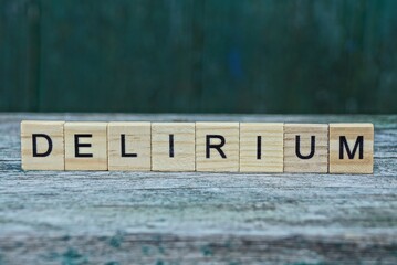 word delirium made of wooden letters on a gray table on a green background