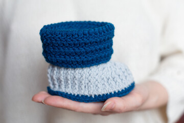 Handicraft Blue and White Knitted Booties on Hands