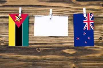 Hanging flags of Mozambique and New Zealand attached to rope with clothes pins with copy space on...