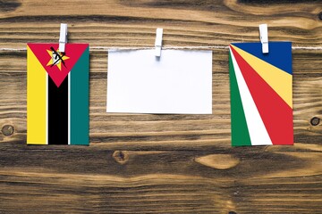 Hanging flags of Mozambique and Seychelles attached to rope with clothes pins with copy space on...
