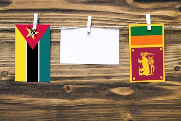 Hanging flags of Mozambique and Sri Lanka attached to rope with clothes pins with copy space on...