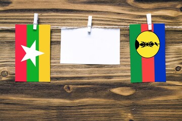 Hanging flags of Myanmar and New Caledonia attached to rope with clothes pins with copy space on...