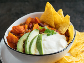 Bowl with home made pumpkin chili with taco chips.