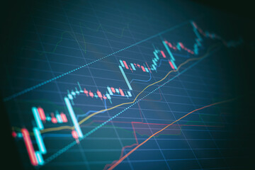 Closeup financial chart with uptrend line candlestick graph in stock market on blue color monitor...