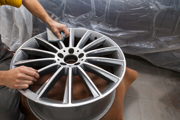 Master body repair man is working on preparing the surface of the aluminum wheel of the car for...