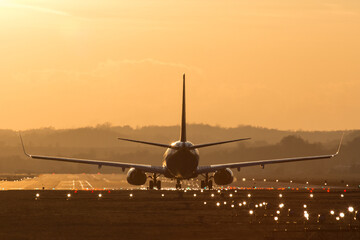 Lądowanie samolotu na lotnisku o zachodzie słońca - obrazy, fototapety, plakaty