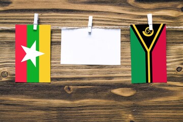 Hanging flags of Myanmar and Vanuatu attached to rope with clothes pins with copy space on white...