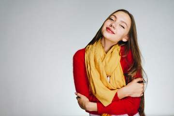 girl with bright lips in a red sweater, cringes and smiles with pleasure