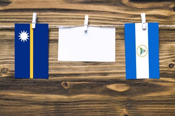 Hanging flags of Nauru and Nicaragua attached to rope with clothes pins with copy space on white...