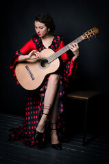 Obraz na płótnie Canvas Carmen beautiful woman in red dress, with guitar on dark background