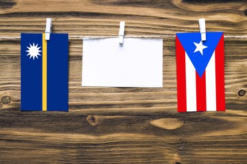 Hanging flags of Nauru and Puerto Rico attached to rope with clothes pins with copy space on white...