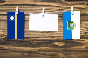 Hanging flags of Nauru and San Marino attached to rope with clothes pins with copy space on white...